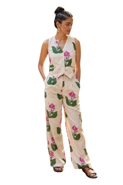 Woman in floral print jumpsuit standing in a garden.